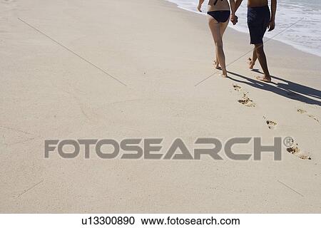 Low section of a couple walking at beach View Large Photo Image Stock Image - Low section of a couple walking at beach. Fotosearch