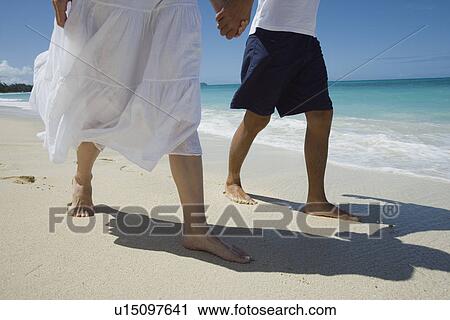 Low section of a couple walking on beach View Large Photo Image Stock Image - Low section of a couple walking on beach. Fotosearch