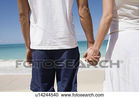 Midsection of a couple holding hands at beach View Large Photo Image Stock Image - Midsection of a couple holding hands at beach. Fotosearch