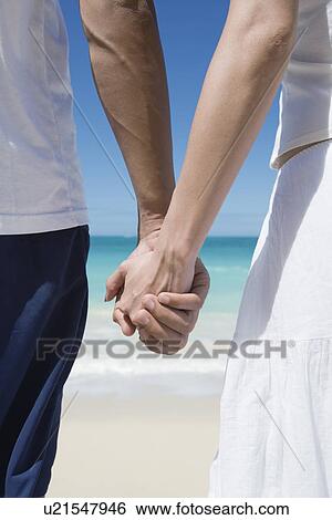 Midsection of a couple holding hands View Large Photo Image Stock Photograph - Midsection of a couple holding hands. Fotosearch