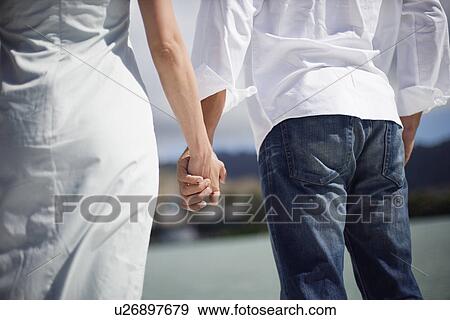 Midsection of man and woman holding hands of each other View Large Photo Image Stock Photo - Midsection of man and woman holding hands of each other. Fotosearch