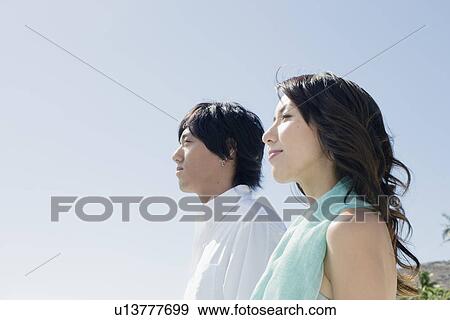 Profile of a young couple standing together View Large Photo Image Stock Photo - Profile of a young couple standing together. Fotosearch