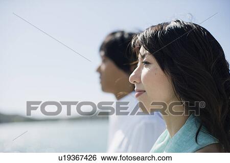 Stock Photograph - Profile of a young couple standing together. Fotosearch