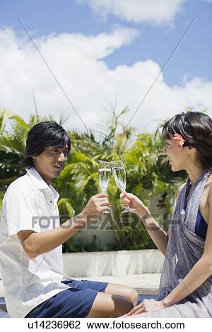 Stock Image - Profile of a young couple toasting wineglass. Fotosearch
