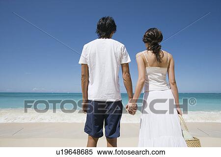 Stock Photography - Rear view of a young couple at beach. Fotosearch