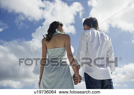 Picture - Rear view of a young couple holding hands. Fotosearch