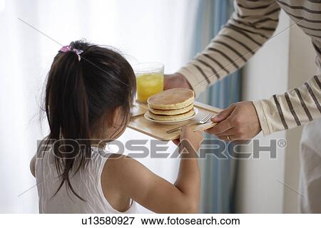 Stock Photo - A girl holding a tray with some pancakes. Fotosearch