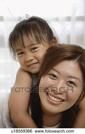 Stock Photograph - A mother carrying her daughter on her back. Fotosearch