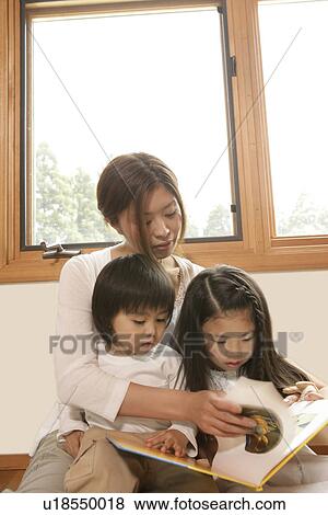 Stock Photo - A mother telling stories to her children from a story book. Fotosearch