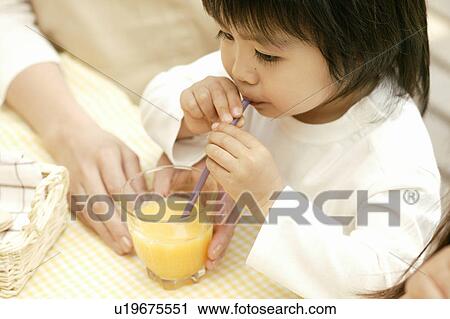 Stock Image - A small boy drinking juice with the help of a straw. Fotosearch