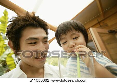 Stock Image - A young boy makes bubbles out of the juice he is drinking. Fotosearch