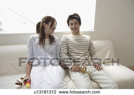 A young couple sitting on a sofa View Large Photo Image Stock Image - A young couple sitting on a sofa. Fotosearch