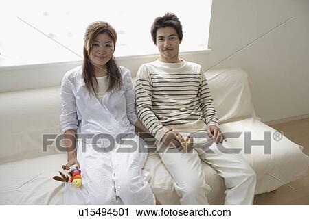 Stock Image - A young couple sitting on a sofa. Fotosearch