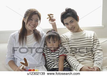 A young family sitting on a sofa View Large Photo Image Stock Photo - A young family sitting on a sofa. Fotosearch