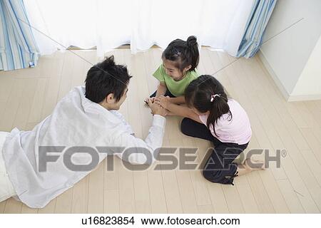 Picture - A young father playing with two girls. Fotosearch