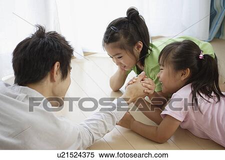 Stock Photography - A young father playing with two girls. Fotosearch