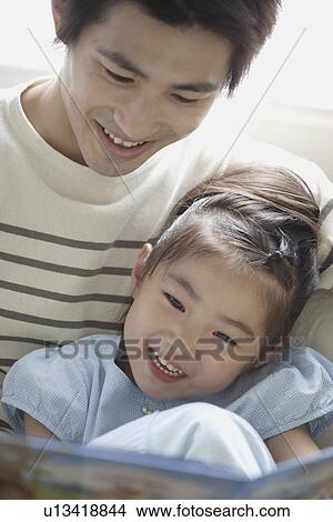 A young father reading a book to his daughter View Large Photo Image Picture - A young father reading a book to his daughter. Fotosearch