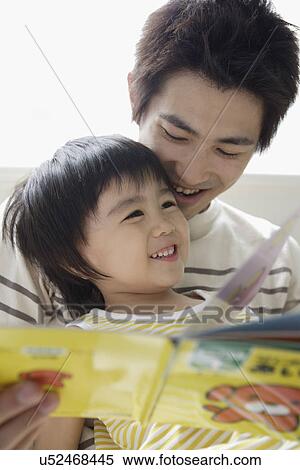 Stock Photography - A young father reading a book to his son. Fotosearch