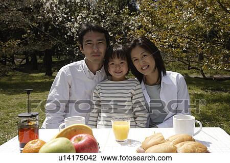 Stock Image - Portrait of a family sitting by breakfast table. Fotosearch