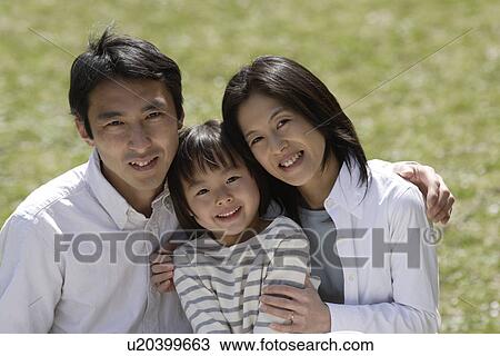 Stock Image - Portrait of parents smiling with daughter. Fotosearch