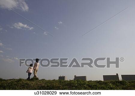 Rear view of a mother and daughter walking on grass View Large Photo Image Stock Photo - Rear view of a mother and daughter walking on grass. Fotosearch