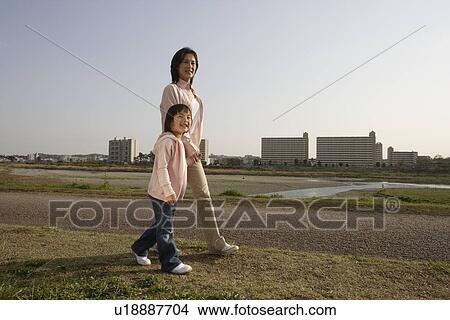 Picture - Side view of a mother and daughter walking on pathway. Fotosearch