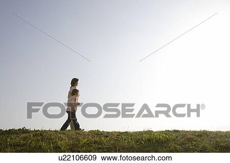 Side view of a mother and daughter walking on grass View Large Photo Image Stock Photo - Side view of a mother and daughter walking on grass. Fotosearch