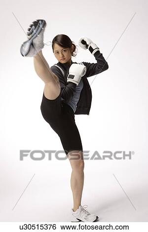 Stock Photograph - Portrait of a young woman kicking. Fotosearch