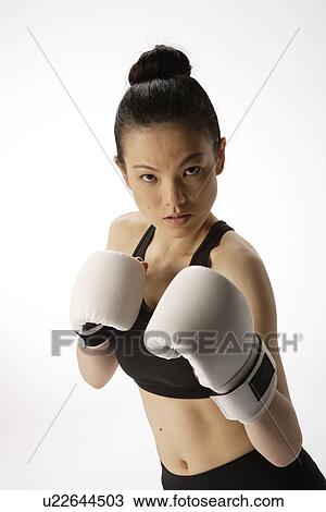 Stock Image - Portrait of a young woman with boxing gloves. Fotosearch