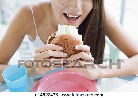 Stock Photograph - A young woman eating burger. Fotosearch