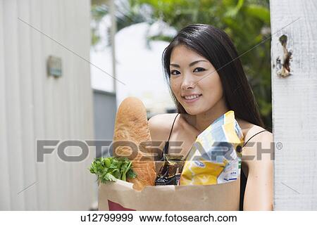A young woman holding paper bag with groceries View Large Photo Image Stock Photo - A young woman holding paper bag with groceries. Fotosearch
