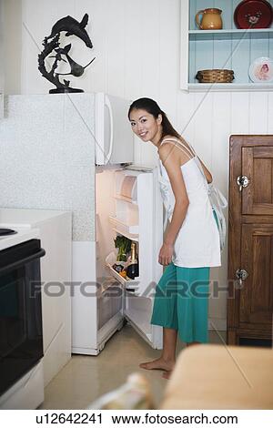 Stock Image - A young woman opening refrigerator. Fotosearch