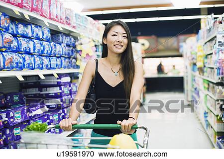 Stock Image - A young woman shopping in supermarket. Fotosearch
