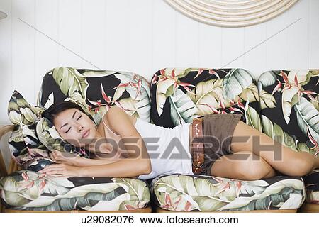 Stock Photograph - A young woman sleeping on couch. Fotosearch