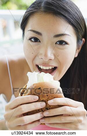 Portrait of a young woman eating burger View Large Photo Image Picture - Portrait of a young woman eating burger. Fotosearch