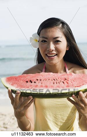 Stock Image - Portrait of a young woman holding watermelon. Fotosearch