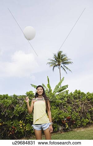Stock Image - Portrait of a young woman holding balloon. Fotosearch