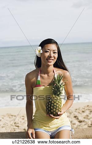 Stock Photo - Portrait of a young woman holding pineapple. Fotosearch