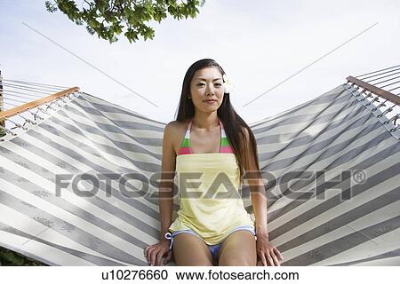 Stock Image - Portrait of a young woman sitting on a hammock. Fotosearch