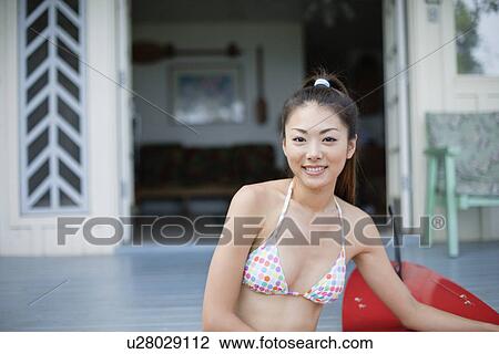 Stock Image - Portrait of a young woman sitting on steps. Fotosearch