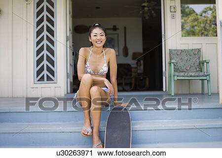 Stock Image - Portrait of a young woman sitting on steps. Fotosearch