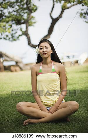 Stock Photo - Portrait of a young woman sitting on grass. Fotosearch