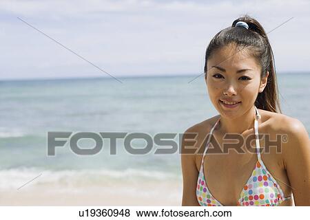 Stock Photo - Portrait of a young woman smiling on beach. Fotosearch