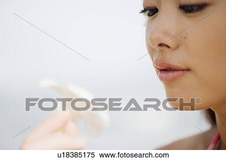 Stock Photography - View of a young woman looking at flower. Fotosearch