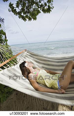 Stock Image - View of a young woman lying on a hammock. Fotosearch