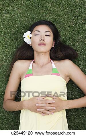 View of a young woman lying on grass View Large Photo Image Stock Image - View of a young woman lying on grass. Fotosearch