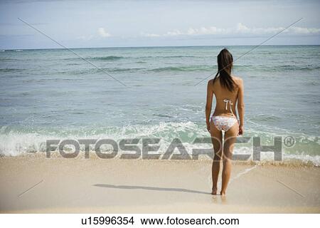 Picture - View of a young woman standing on beach. Fotosearch