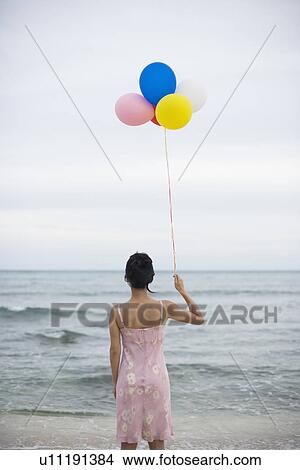 A woman holding balloons in beach View Large Photo Image Picture - A woman holding balloons in beach. Fotosearch