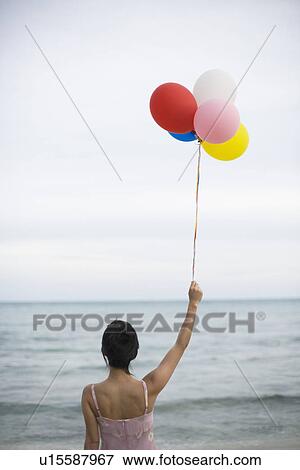 A woman holding balloons in beach View Large Photo Image Stock Photo - A woman holding balloons in beach. Fotosearch