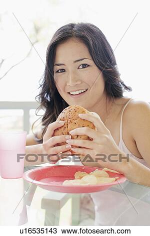 Stock Image - A woman holding burger. Fotosearch